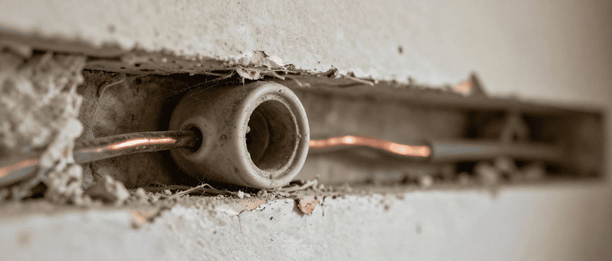 Détail d'une installation électrique extérieure avec conduit en cuivre dans un mur en construction, prêt pour l'aménagement extérieur.